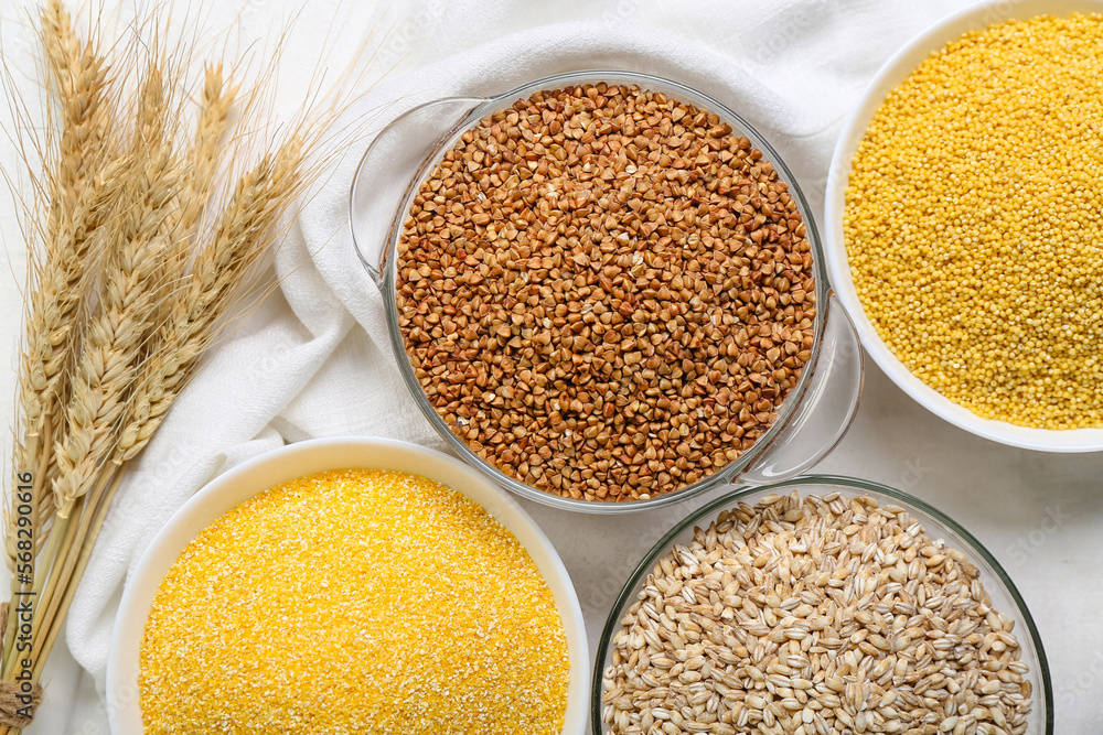 Bowls with different cereals and spikelets on light background, closeup Bowls with different cereals and spikelets on light background, closeup