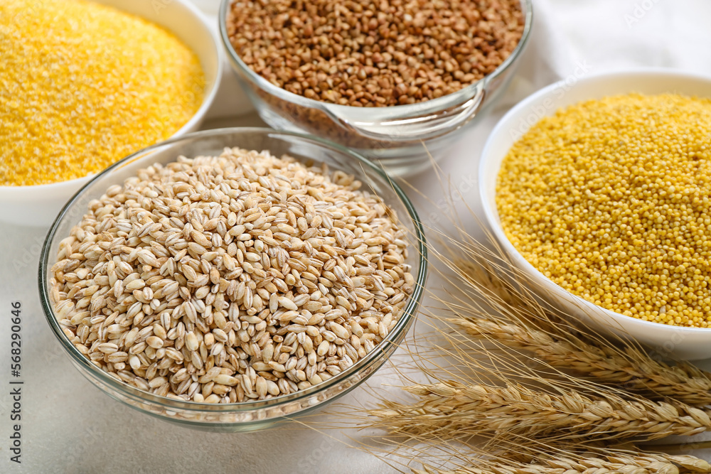 Bowls with different cereals and spikelets on light background, closeup Bowls with different cereals and spikelets on light background, closeup