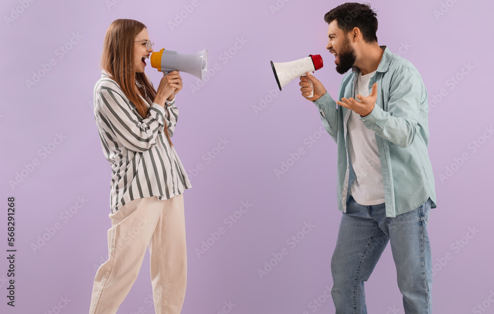 Young couple shouting into megaphones on lilac background Young couple shouting into megaphones on lilac background