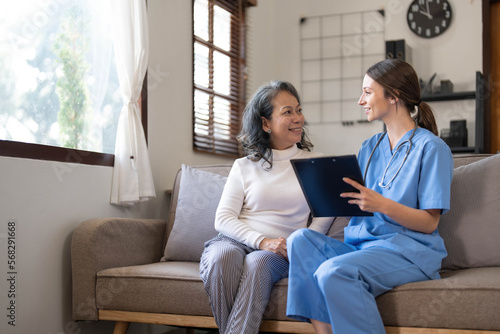 Asian nurse showing health checkup report to grandmather and giving advice. medical assisted living visit senior patient at home. Home nursing and healthcare caregiver concept photo