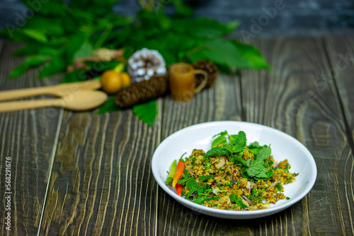 Spicy minced catfish salad with herbs northeastern thai food mellow taste served on a dark wooden table.