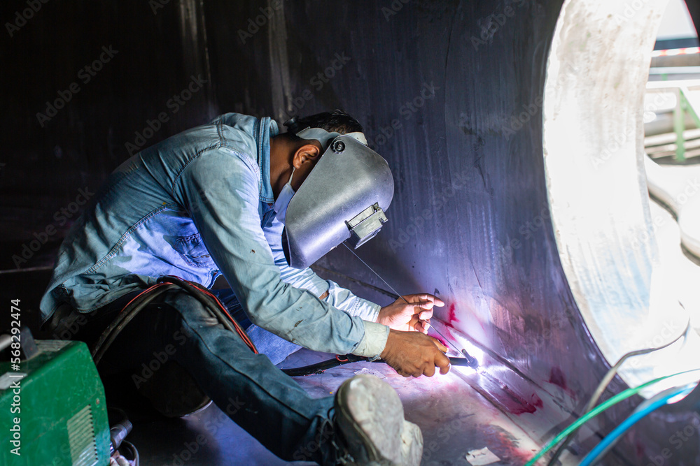 Welding  arc argon worker male repaired metal is welding sparks industrial construction tank