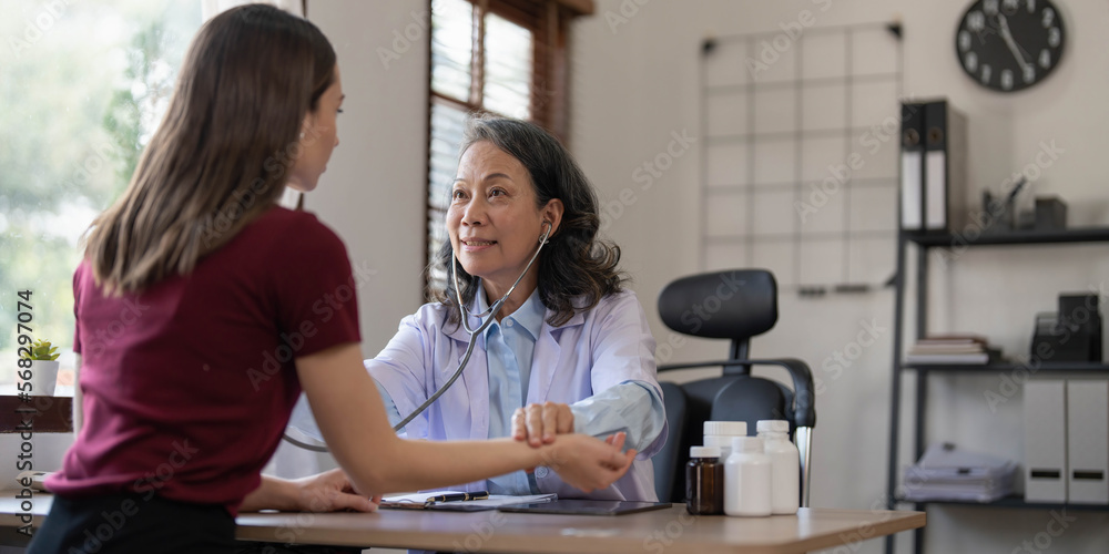 Fototapeta premium Middle aged female pediatrician listening to young woman's complaints with health problems And write down on the medical history paper during the treatment. health concept