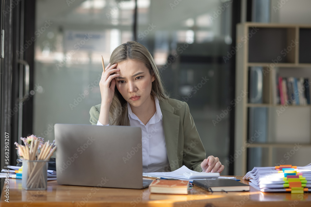 Asian businesswoman are stressed and tired from work sitting at desk in the office, feeling sick at work, stress from work. Asian businesswoman are stressed and tired from work sitting at desk in the office, feeling sick at work, stress from work.