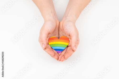 Female hands with rainbow paper heart isolated on white background. 