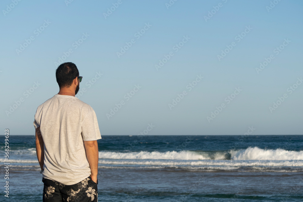 Man walking relaxedly on the beach looking towards the sea
