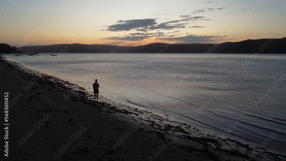 Naklejka premium man contemplating the sunset on the beach