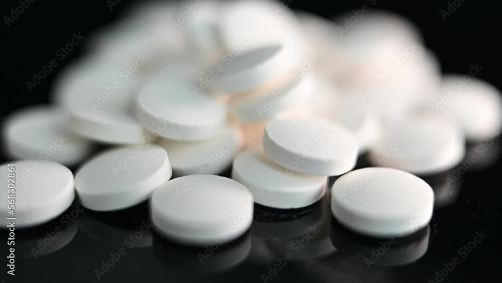 Close up of a pile of generic white pills in on a reflective surface Close up of a pile of generic white pills in on a reflective surface