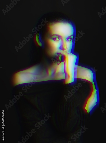 Studio portrait of beautiful woman with wet hairstyle. Model looking at camera and thinking by holding hand palm near mouth. RGB color split effect applied. Futuristic looking style