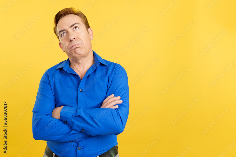 Bored mature man looking up with arms crossed Bored mature man looking up with arms crossed
