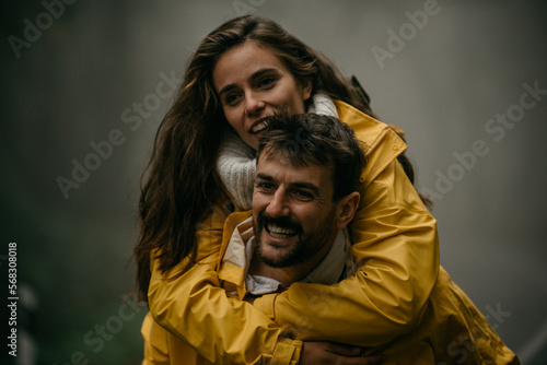 Cheerful embraced couple having fun while piggybacking on an autumn day outdoors. 