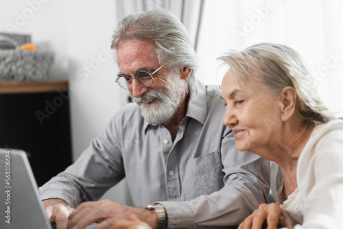 Older caucasian couple with tablet computer in living room at home	