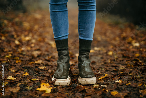 Female footwear boots standing in the forest path covered with earth and leaves.