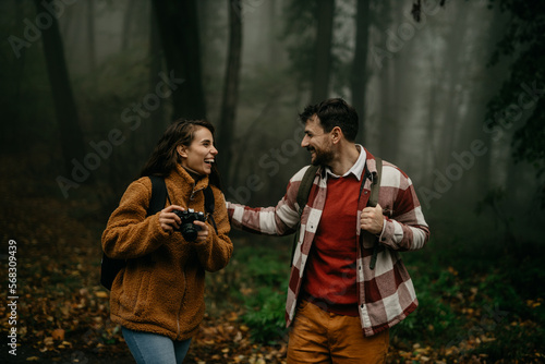People hiking - happy hiker couple trekking as part of healthy lifestyle outdoors activity. Young multiracial couple walking in nature on a cold day