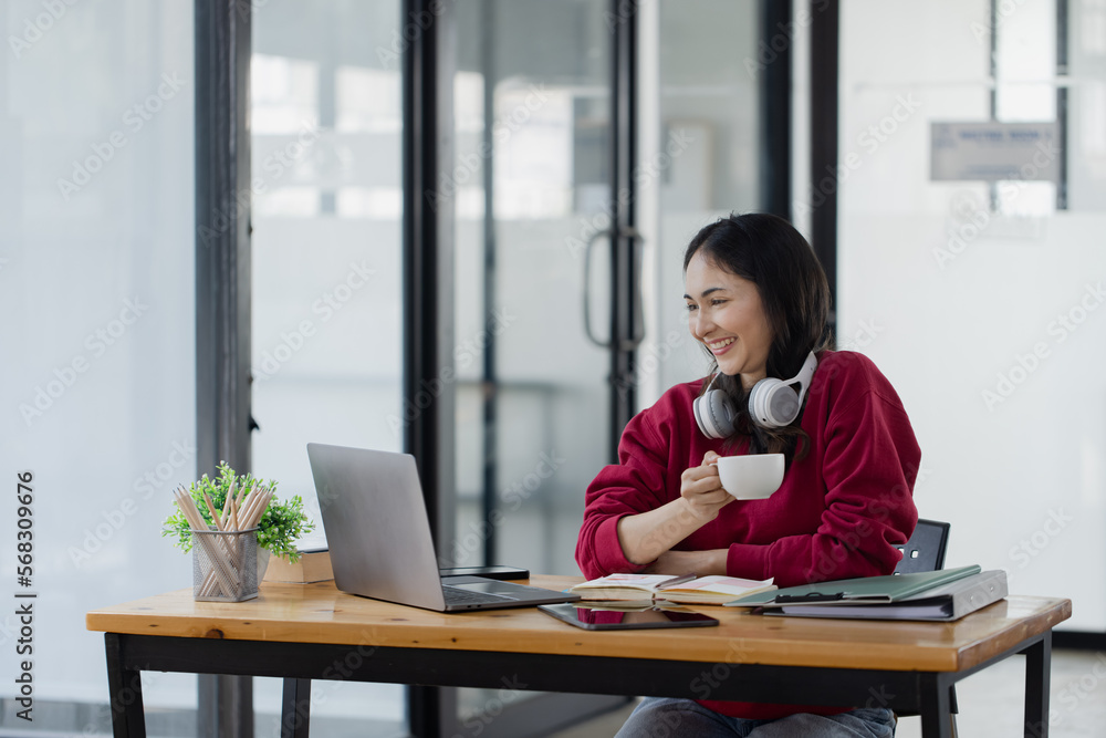 Happy smiling young asian business woman wear headphones working online sitting at desk in the office, Happy smiling young asian business woman wear headphones working online sitting at desk in the office,