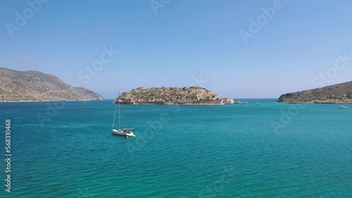 Cruise to the island of Spinalonga. Small boat on the blue lagoon. Spinalonga fortress on the island of Crete, Greece. Architecture on the island.