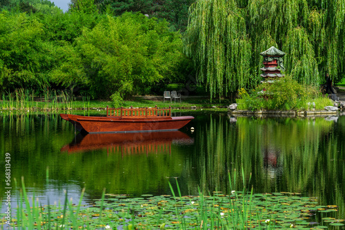 Wooden boat and Chinese pagoda by the lake. Summer landscape.