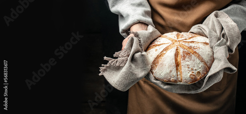 woman holding fresh bread from the oven, baking homemade sourdough bread. Food preparation. Culinary, cooking, bakery concept. Long banner format
