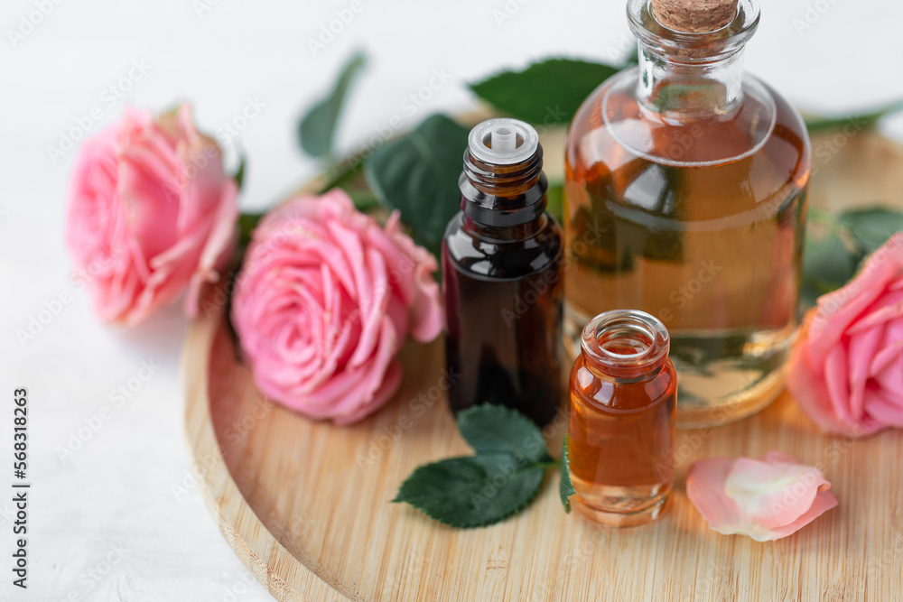 Aromatherapy. Concept of pure organic essential rose oil. Elixir with plant based floral or herbal ingredients. Pink flowers extract. Spa atmosphere with candle, towel. White background Aromatherapy. Concept of pure organic essential rose oil. Elixir with plant based floral or herbal ingredients. Pink flowers extract. Spa atmosphere with candle, towel. White background