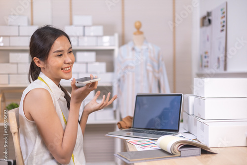 Beautiful asian woman fashion designer standing in the clothing store and studio. In front of the camera to recording vlog video live streaming.Business online influencer on social media.