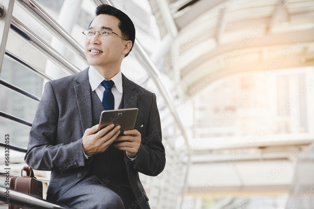 Handsome asian businessman holding digital tablet, wear suit and eyeglasses. Leadership executive business guy get successful of business. Male get confidence. Professional businessman portrait Handsome asian businessman holding digital tablet, wear suit and eyeglasses. Leadership executive business guy get successful of business. Male get confidence. Professional businessman portrait