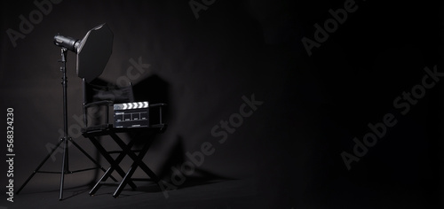 Black Director chair and clapper boardand studio light on black background.