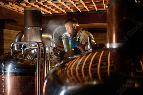 Photos Brewer adding ferment with yeast or hop into beer tank