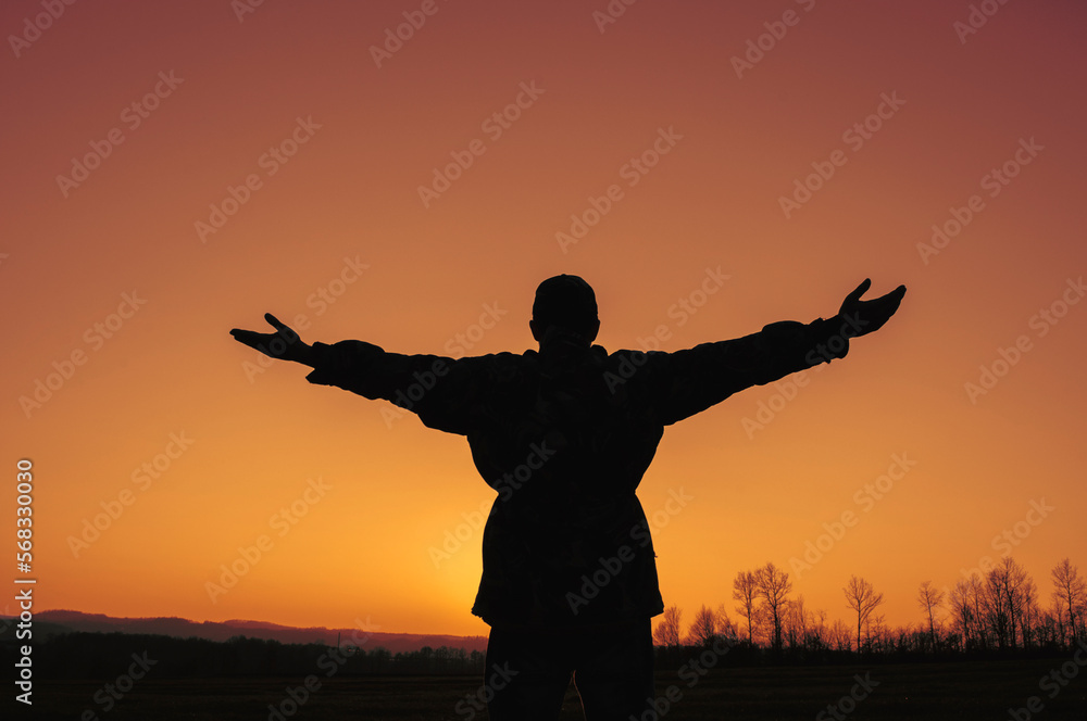 Silhouette of a man in countryside with arms outstretched Silhouette of a man in countryside with arms outstretched