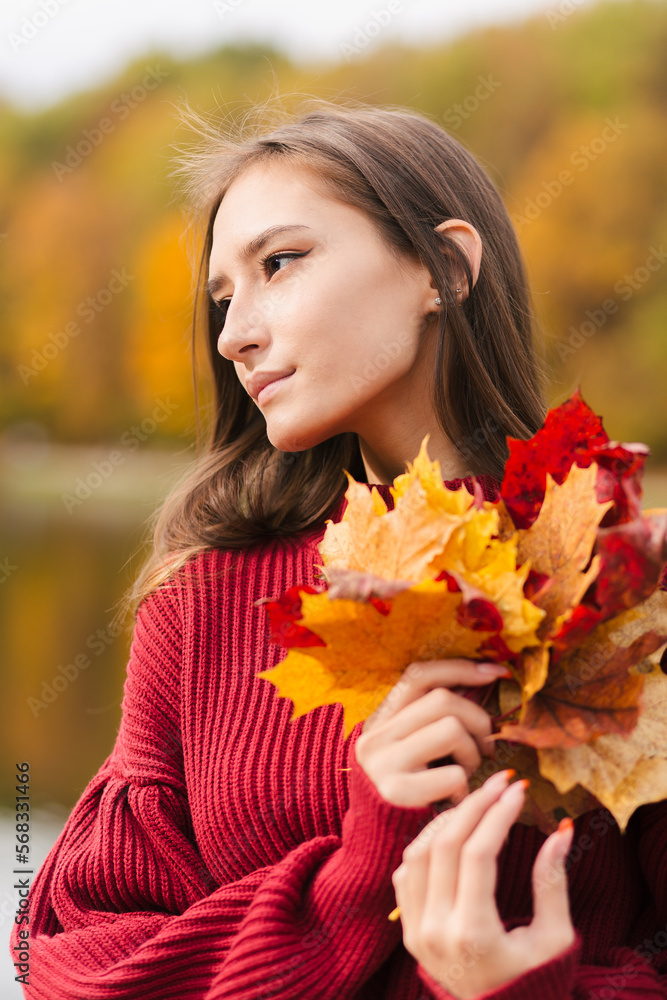 Young asian woman in red jumper holding yellow maple leaves Young asian woman in red jumper holding yellow maple leaves