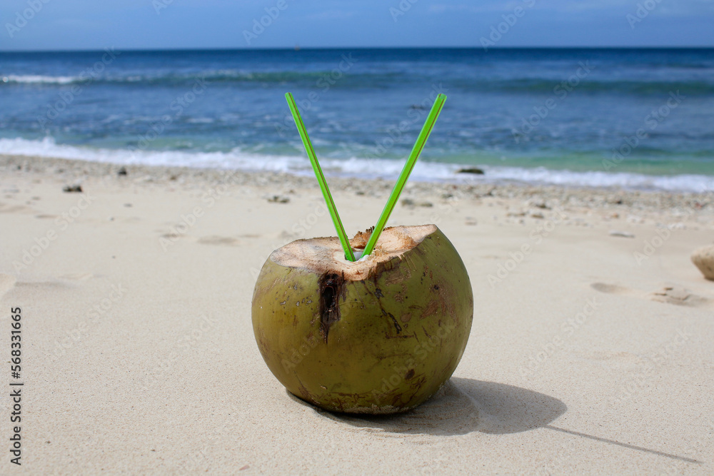 Coconut cocktail with two straws on a sandy beach. Coconut drink on the beach. Coconut cocktail with two straws on a sandy beach. Coconut drink on the beach.