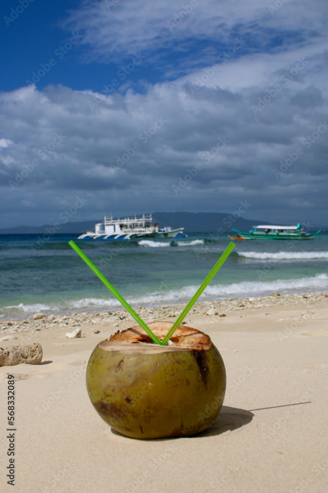 Coconut cocktail with two straws on a sandy beach. Coconut drink on the beach. Coconut cocktail with two straws on a sandy beach. Coconut drink on the beach.