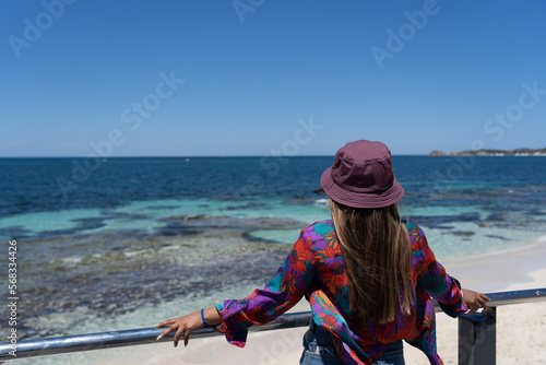 Sea and beach landscape of Rottnest Island in Perth, WA Australia with a beautiful anonymous women lwith flowers top and a bony looking to the horizon