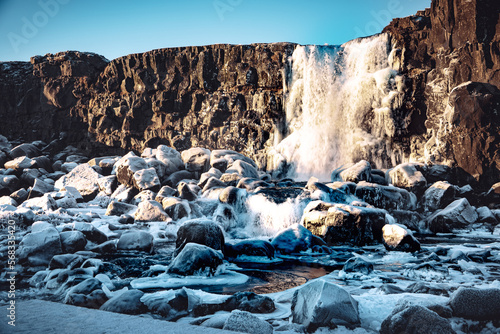 Iceland Öxarárfoss frozen waterfall on the rocks in winter sun 