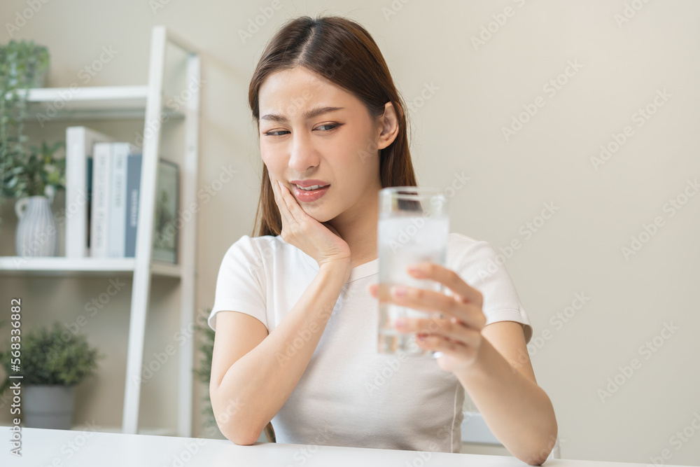 Suffering from toothache, asian young woman, girl touch cheek, face expression ache or feel pain, sensitive molar teeth, hand holding glass of water with ice, inflammation when drink cold, healthcare. Suffering from toothache, asian young woman, girl touch cheek, face expression ache or feel pain, sensitive molar teeth, hand holding glass of water with ice, inflammation when drink cold, healthcare.