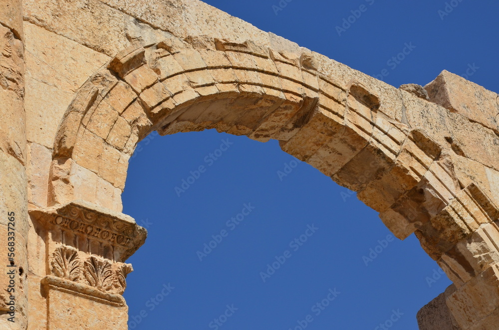 Sunny temples, arches, the Nymphaeum, stone ornaments, columns and column bases on the ruins of the city of Jerash in Jordan.
