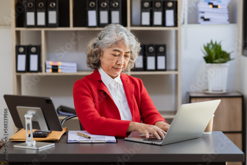 Asian senior woman using laptop computer and working planning at office desk.