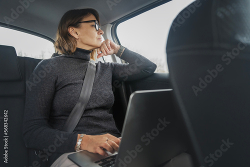 Adult aattractive caucasian businesswoman using laptop while sitting on passenger seat of car © olezzo