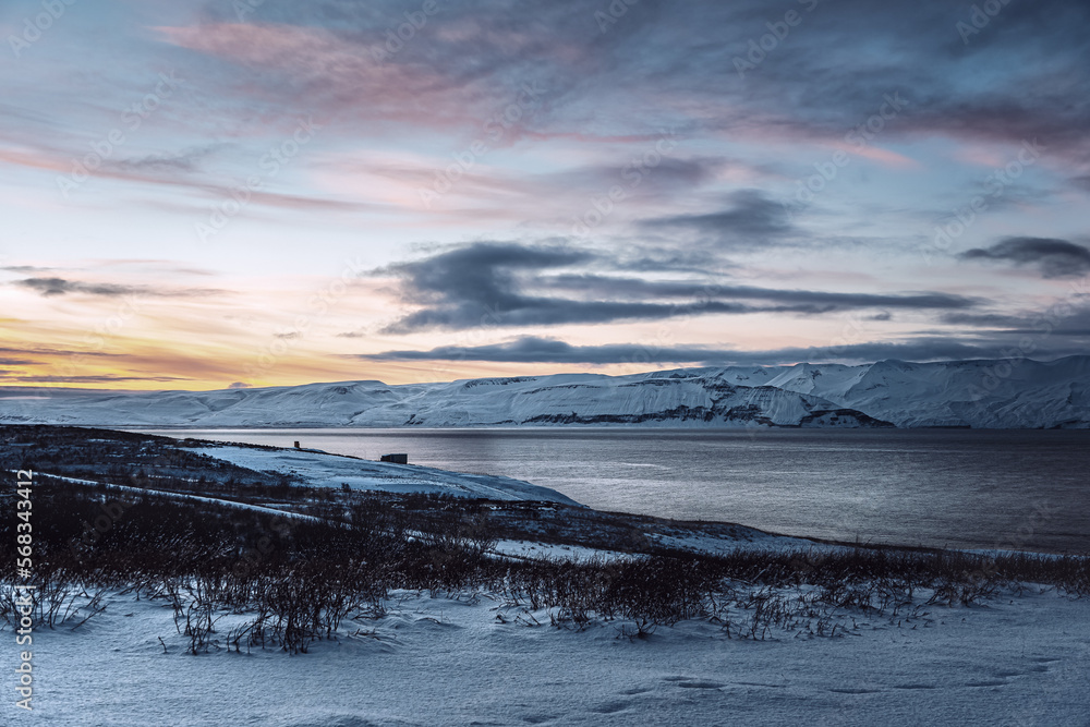 Iceland snow covered mountain landscape with red orange sunset over bay Iceland snow covered mountain landscape with red orange sunset over bay