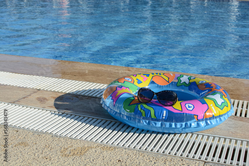 bright inflatable ring, on which sunglasses lie, next to the pool