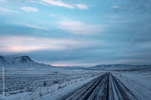 Iceland sunset or sunrise with cloudy blue yellow sky over winter snow road landscape