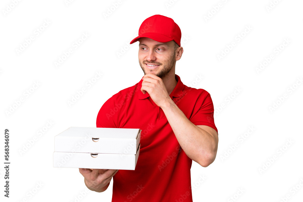 Pizza delivery man with work uniform picking up pizza boxes over isolated chroma key background looking to the side and smiling Pizza delivery man with work uniform picking up pizza boxes over isolated chroma key background looking to the side and smiling