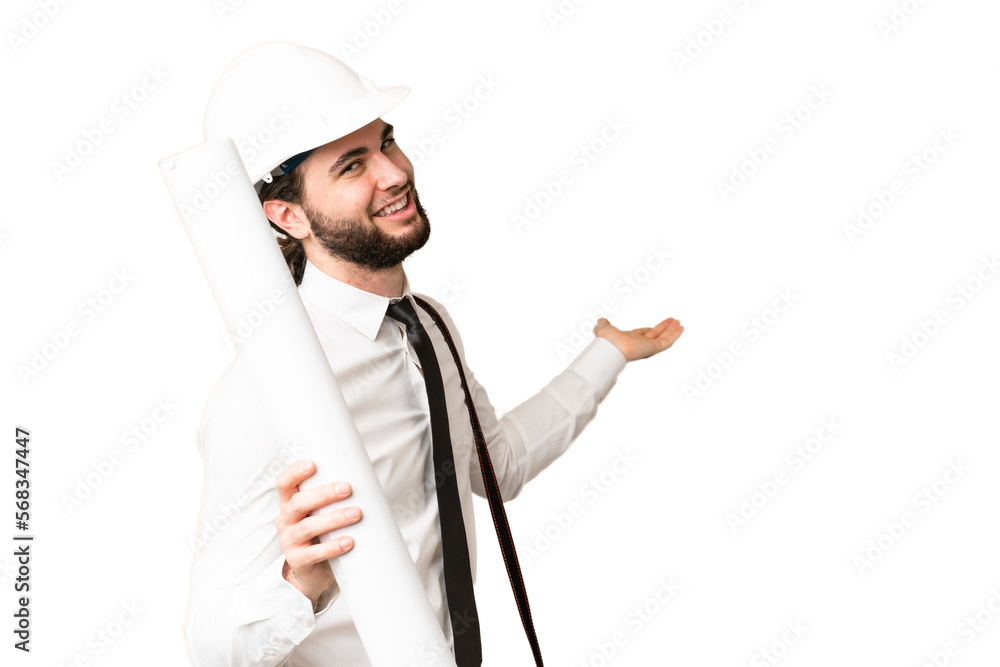 Young architect man with helmet and holding blueprints over isolated chroma key background extending hands to the side for inviting to come Young architect man with helmet and holding blueprints over isolated chroma key background extending hands to the side for inviting to come