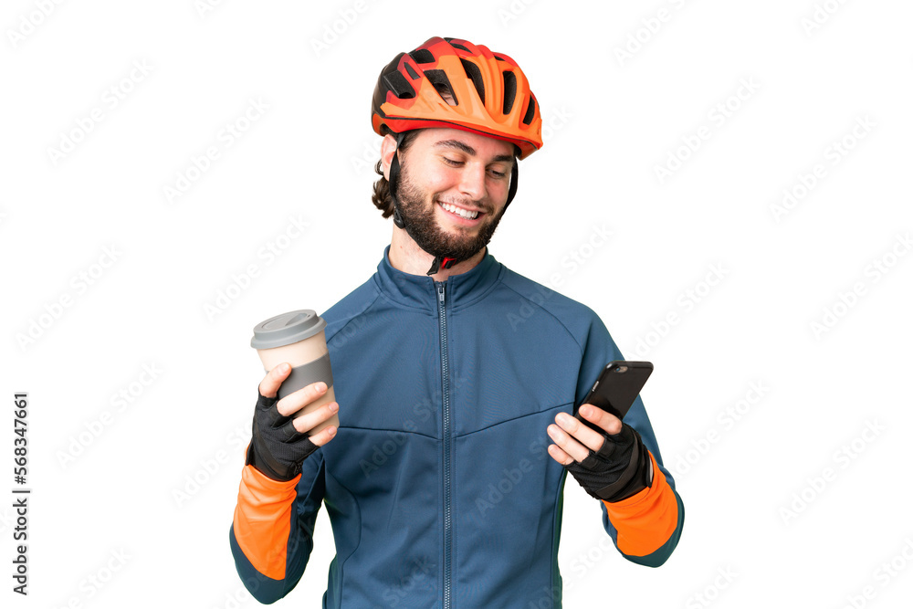 Young cyclist man over isolated chroma key background holding coffee to take away and a mobile Young cyclist man over isolated chroma key background holding coffee to take away and a mobile