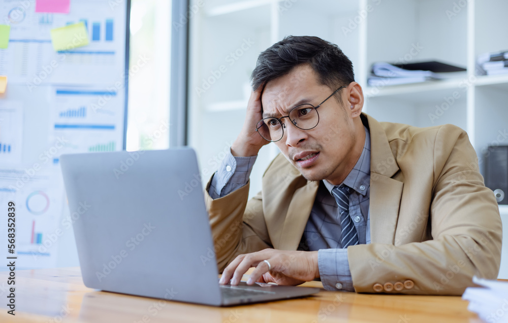 Stressed and sad Asian man sitting at desk in office, freelance business, Asian man emotion feelings, sad upset face. Stressed and sad Asian man sitting at desk in office, freelance business, Asian man emotion feelings, sad upset face.