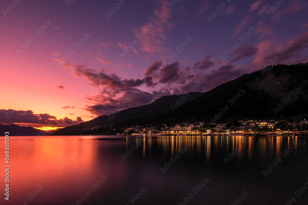 Sunset afterglow lighting up Lake Wakatipu and the town of Queenstown on the South Island of new Zealand with Walter Peak in the distance