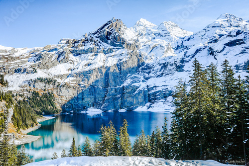 beautiful mountain landscape with a little blue lake with blue water blue sky and snow on the trees during a sunny day