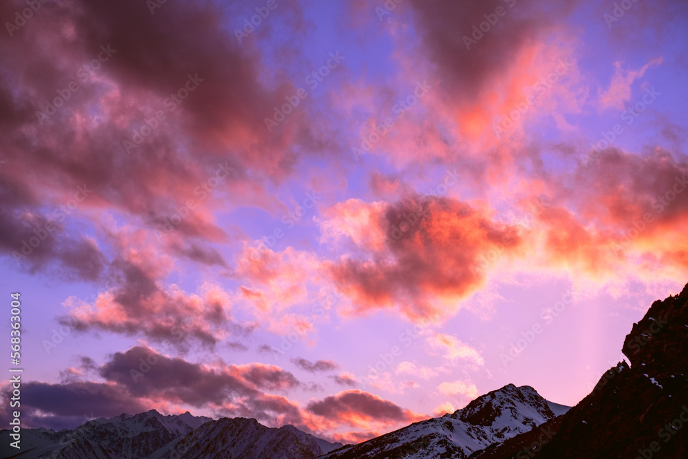 Bizarrely interesting sunset clouds over snow-capped mountain peaks