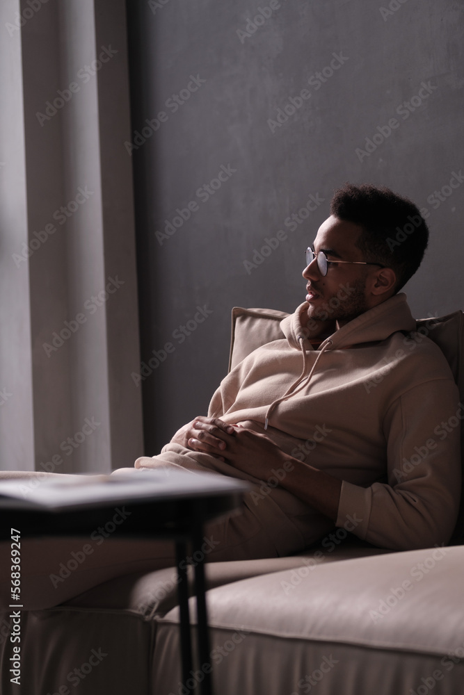 Fototapeta premium Portrait of a cheerful young african american man 20s wearing casual hoody and glasses against black background. copy space isolated