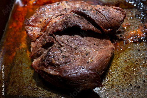 Well cooked medium rare pork stake on greasy cooking pot close up shot.
