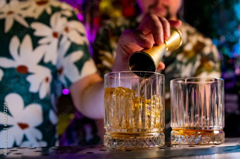 Fototapeta premium Bartender hand pouring whiskey on glass in bar